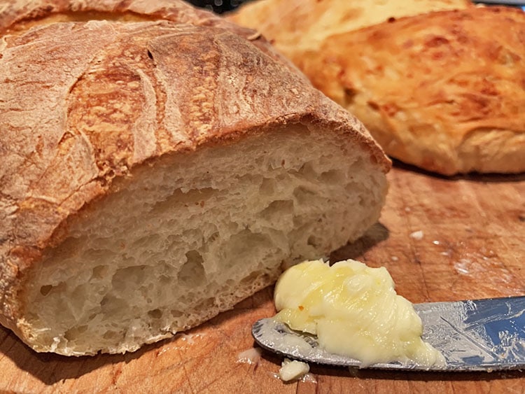 loaf of homemade artisan breads with a dollop of butter on a knife.