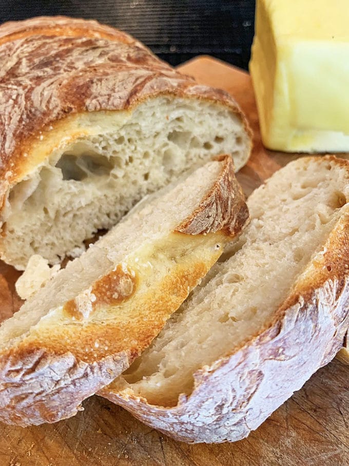 Loaf of homemade bread with butter, on a cutting board.