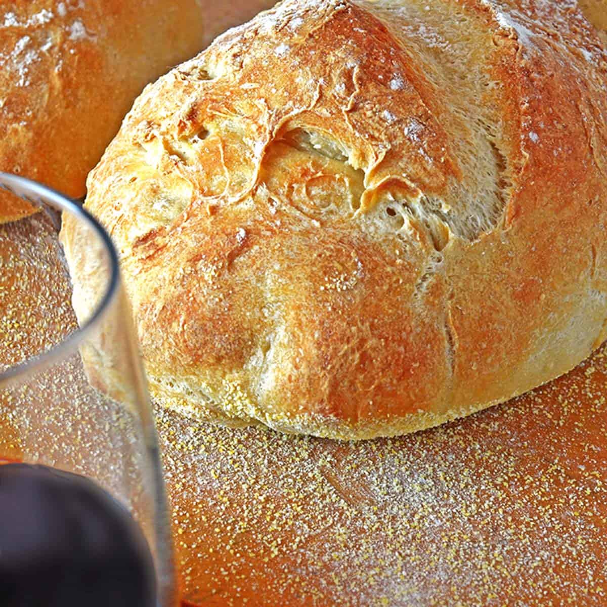 A loaf of bread with a glass of red wine.